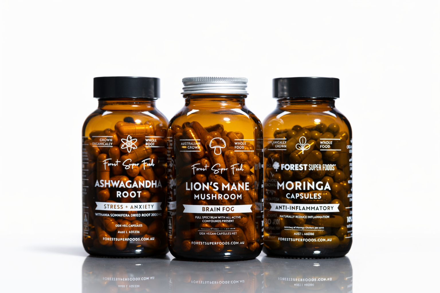 Three amber glass jars containing Ashwagandha Root, Lion's Mane Mushroom, and Moringa Capsules on white background